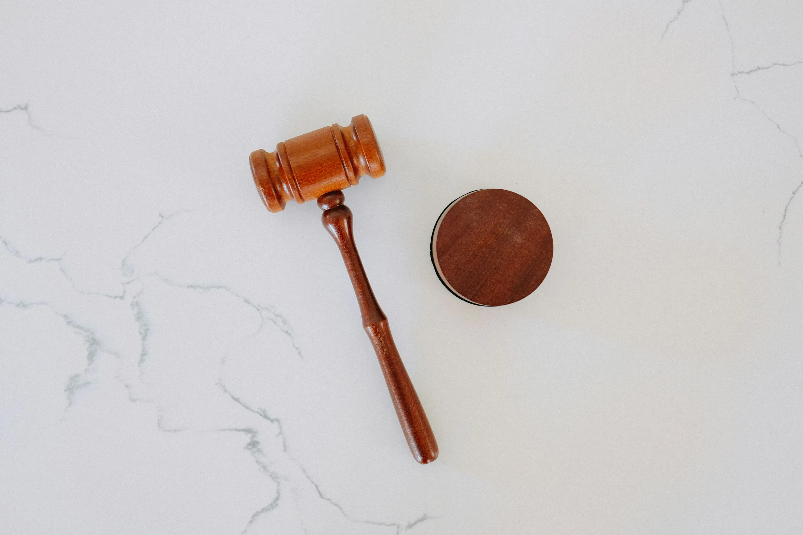 Houten rechtershamer met klankblok op een lichte marmeren ondergrond