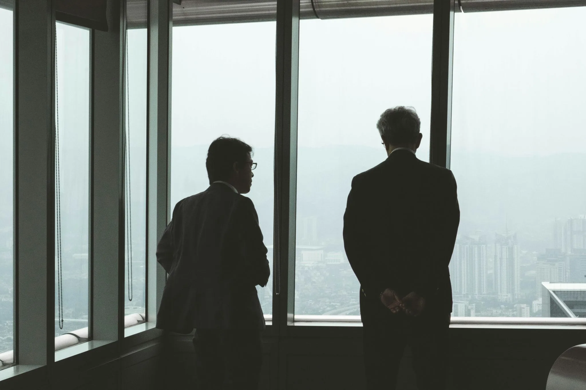 Twee zakelijke professionals kijken uit over de stad vanuit een kantoor met grote ramen